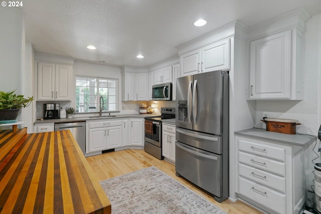 kitchen featuring white cabinets, sink, appliances with stainless steel finishes, and light hardwood / wood-style flooring