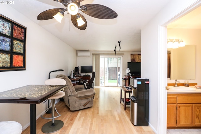 living room featuring ceiling fan, light hardwood / wood-style flooring, sink, and a wall unit AC