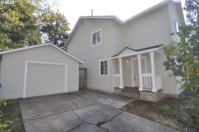 view of front facade with an outbuilding, a garage, and a porch