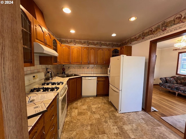 kitchen with light hardwood / wood-style floors, sink, white appliances, and backsplash