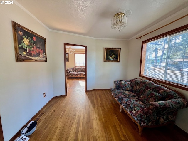 living room with wood-type flooring, a notable chandelier, crown molding, and plenty of natural light