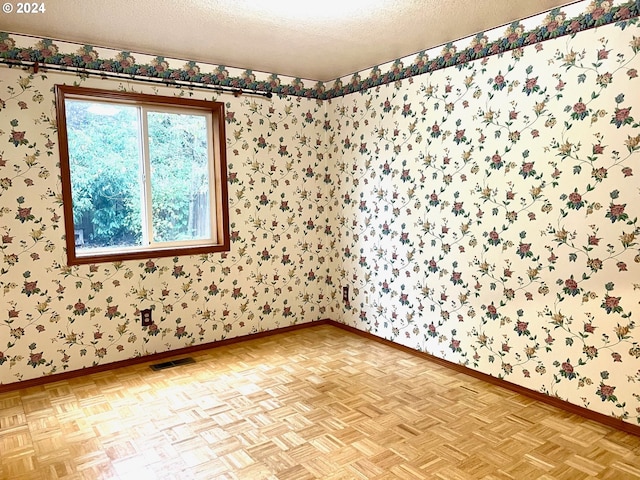 spare room with a textured ceiling and light parquet floors