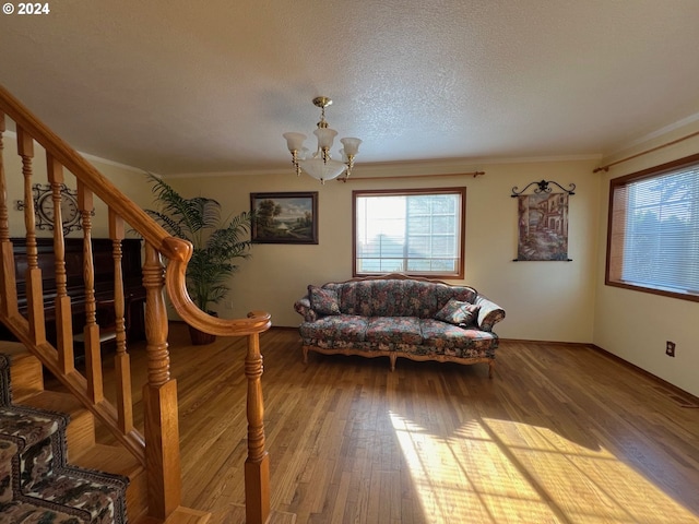 living room with ornamental molding, hardwood / wood-style floors, a textured ceiling, and an inviting chandelier