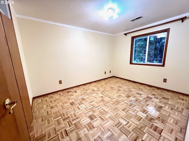 empty room with light parquet flooring, a textured ceiling, and ornamental molding