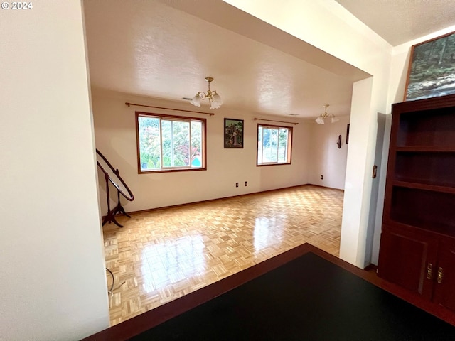 unfurnished room featuring parquet floors, an inviting chandelier, and a textured ceiling