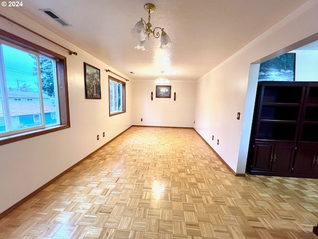 spare room with light parquet flooring and a notable chandelier