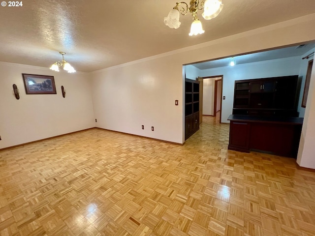 unfurnished living room featuring light parquet flooring, a chandelier, a textured ceiling, and ornamental molding