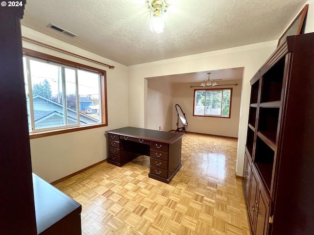 office area featuring light parquet flooring, ceiling fan with notable chandelier, and a textured ceiling