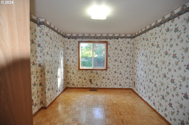 unfurnished room with a textured ceiling and light parquet flooring