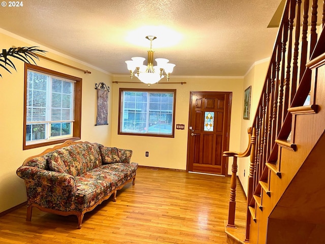 entryway featuring ornamental molding, an inviting chandelier, a textured ceiling, and light hardwood / wood-style floors