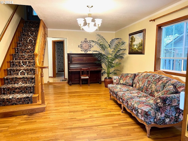 living room featuring ornamental molding, light hardwood / wood-style flooring, a textured ceiling, and a chandelier