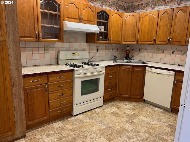 kitchen with tasteful backsplash, white appliances, tile counters, and sink