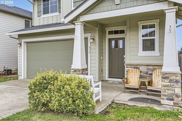 doorway to property with board and batten siding, a porch, concrete driveway, stone siding, and an attached garage