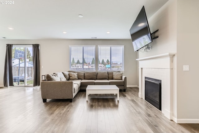 living area with recessed lighting, light wood-style flooring, a fireplace, and baseboards