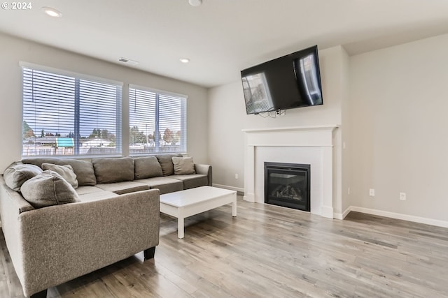 living room featuring visible vents, a fireplace, baseboards, and light wood-style floors