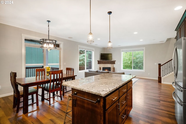 kitchen with stainless steel refrigerator, a wealth of natural light, a center island, and dark wood-type flooring