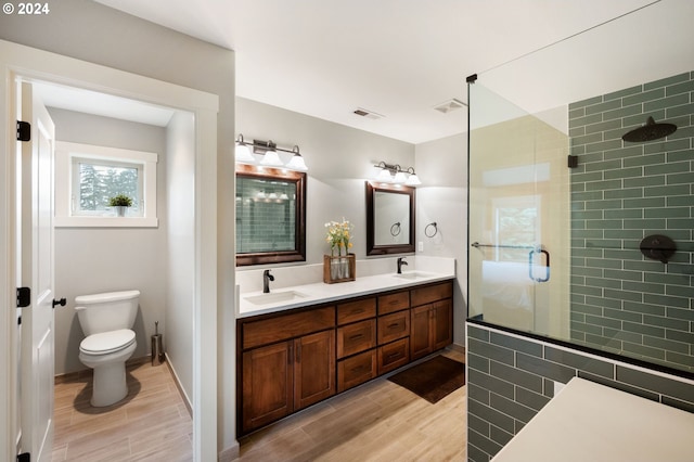 bathroom featuring wood-type flooring, vanity, toilet, and walk in shower