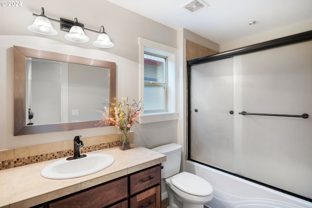 full bathroom featuring vanity, toilet, and bath / shower combo with glass door