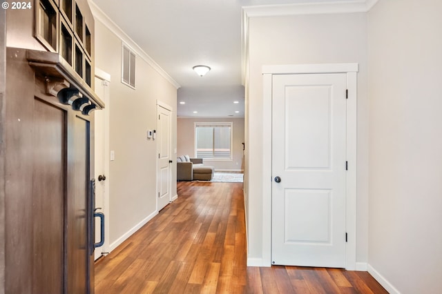 corridor with hardwood / wood-style floors and ornamental molding