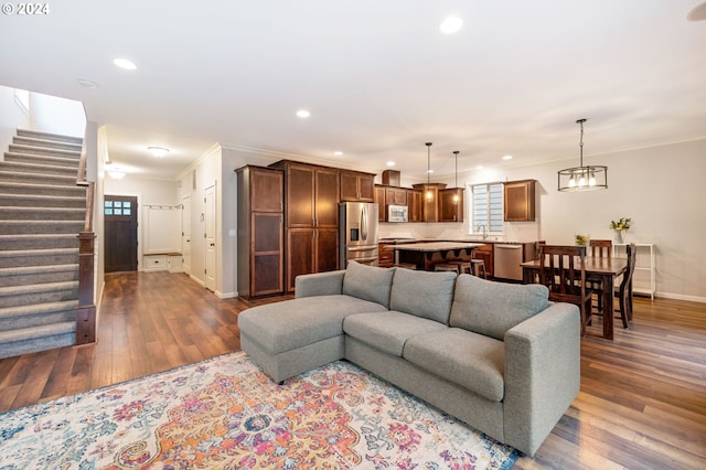 living room featuring a chandelier, dark hardwood / wood-style flooring, and ornamental molding