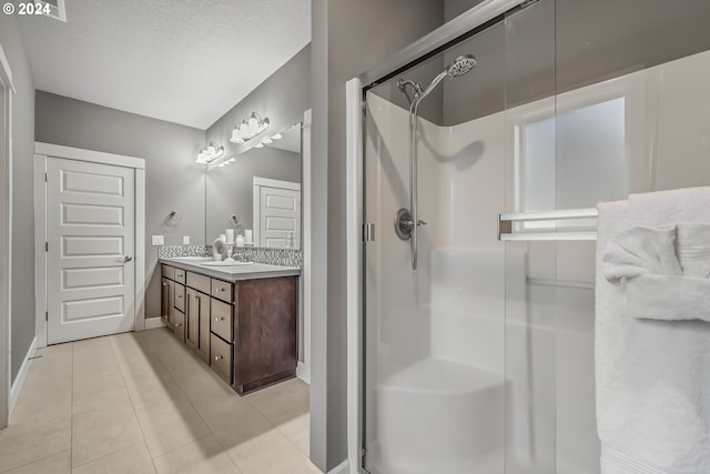 bathroom with vanity, a shower with shower door, a textured ceiling, and tile patterned floors