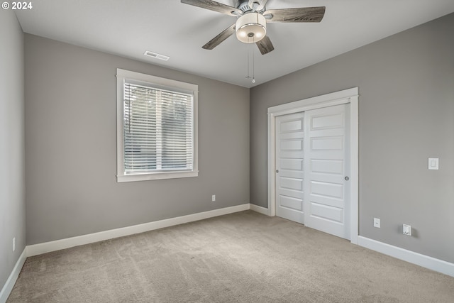 unfurnished bedroom featuring ceiling fan, a closet, and light carpet