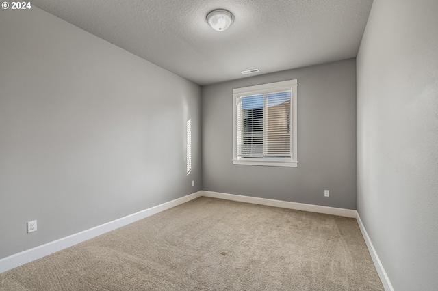 carpeted empty room with a textured ceiling