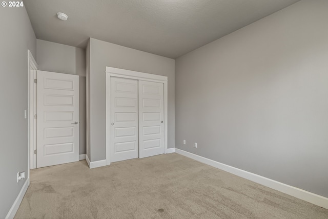 unfurnished bedroom featuring light colored carpet and a closet