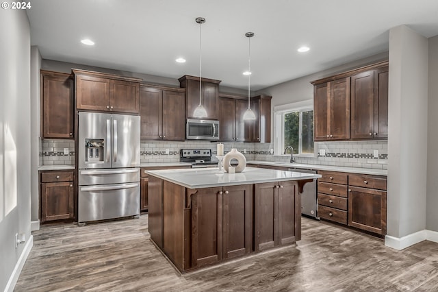 kitchen featuring stainless steel appliances, dark wood-type flooring, a kitchen island, and decorative light fixtures