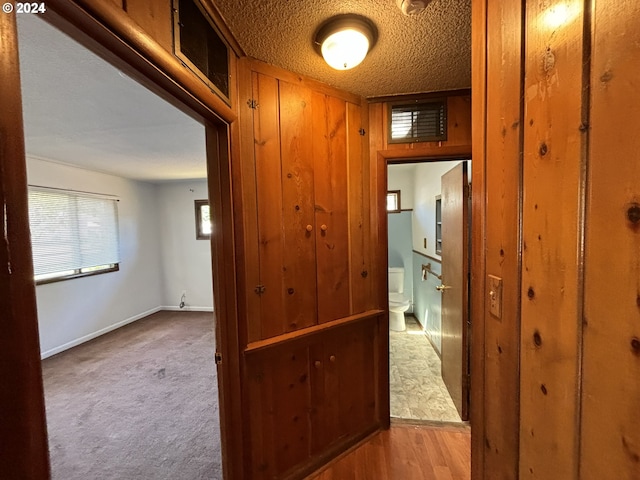 corridor featuring a textured ceiling and light colored carpet