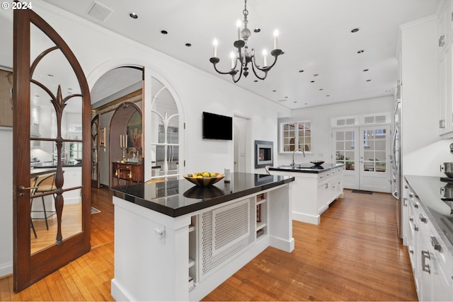 kitchen featuring white cabinetry, light hardwood / wood-style floors, a kitchen island with sink, and french doors