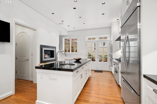 kitchen featuring a kitchen island, sink, appliances with stainless steel finishes, white cabinets, and light hardwood / wood-style floors