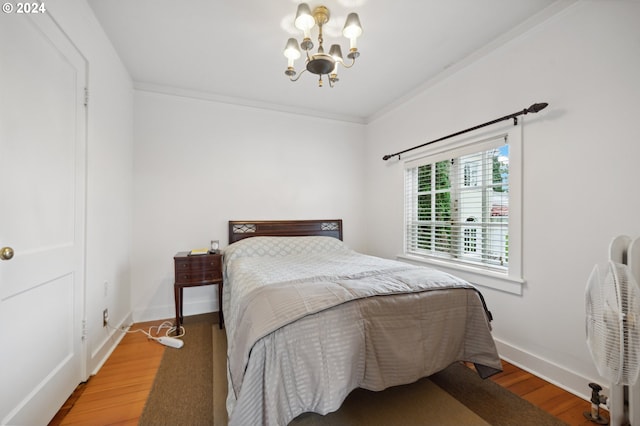 bedroom featuring hardwood / wood-style flooring, a notable chandelier, and ornamental molding