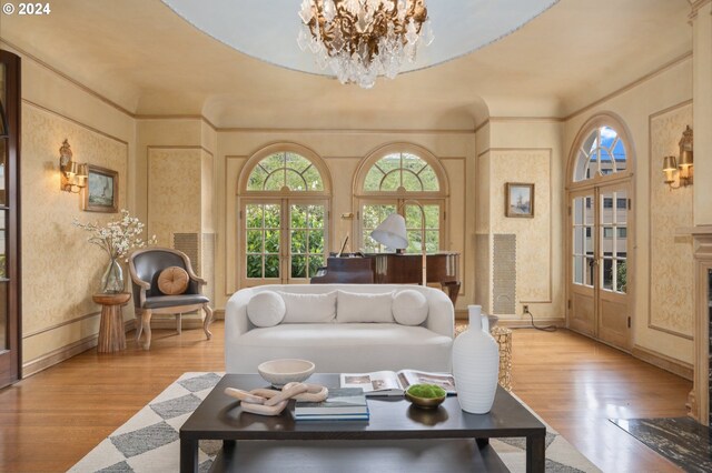 living room featuring light wood-type flooring, crown molding, and a notable chandelier