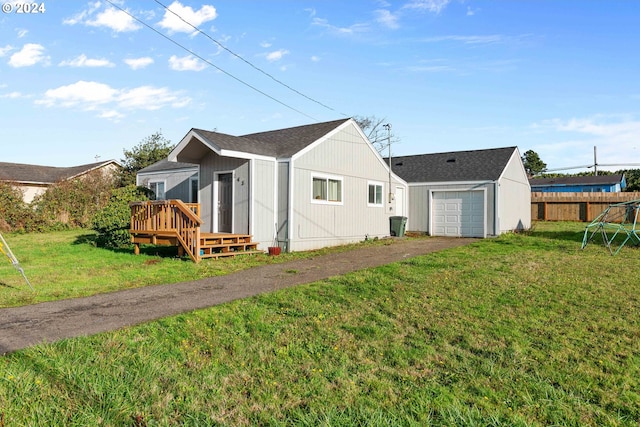 rear view of house with a lawn, a garage, and a deck