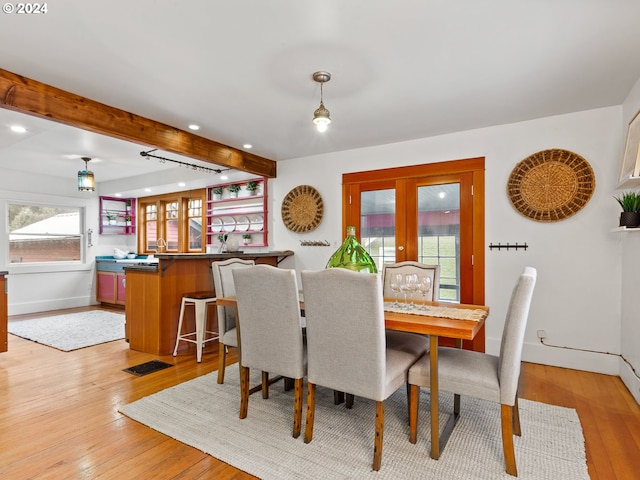 dining area with french doors, light hardwood / wood-style flooring, and beamed ceiling