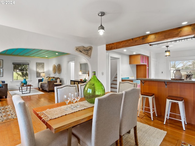 dining space with plenty of natural light, beamed ceiling, and light hardwood / wood-style flooring