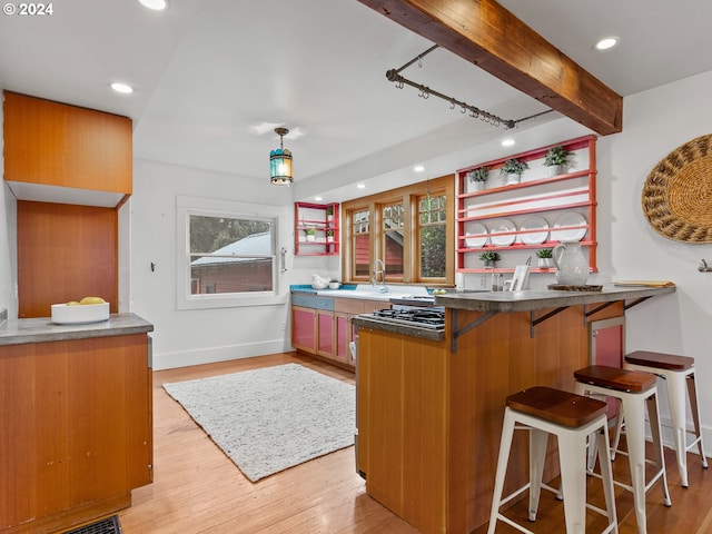 kitchen featuring kitchen peninsula, hanging light fixtures, a breakfast bar, light wood-type flooring, and beam ceiling