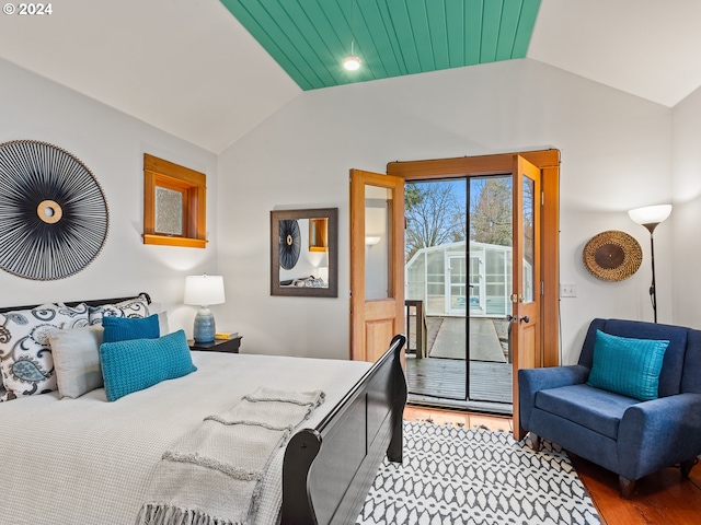 bedroom with lofted ceiling, hardwood / wood-style floors, and access to outside