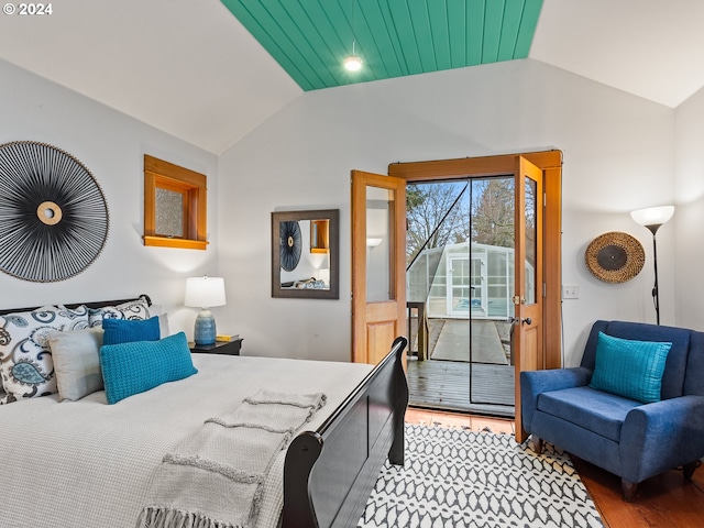 bedroom with hardwood / wood-style flooring, vaulted ceiling, and access to exterior