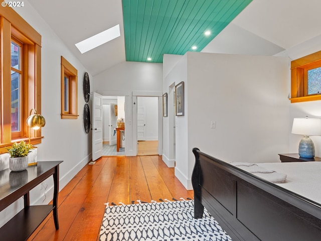 corridor featuring light wood-type flooring and lofted ceiling with skylight