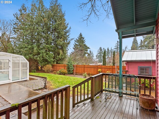 wooden terrace featuring a lawn and an outbuilding