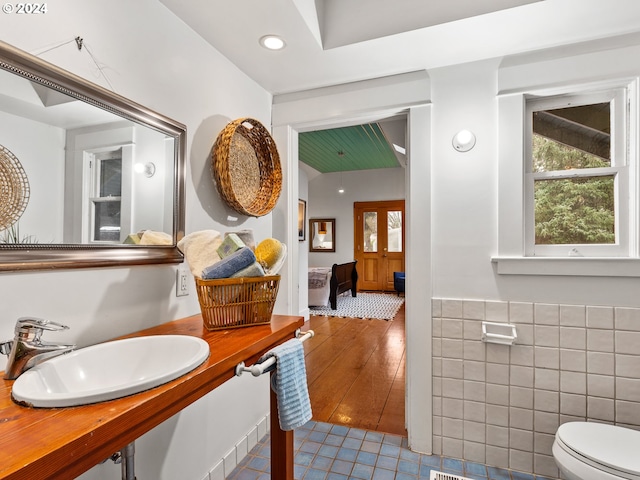 bathroom with sink, tile patterned flooring, tile walls, and toilet