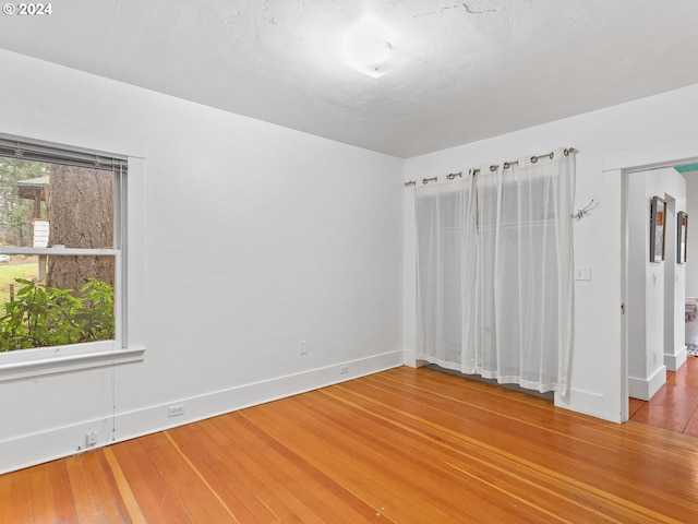 unfurnished bedroom featuring multiple windows and hardwood / wood-style flooring