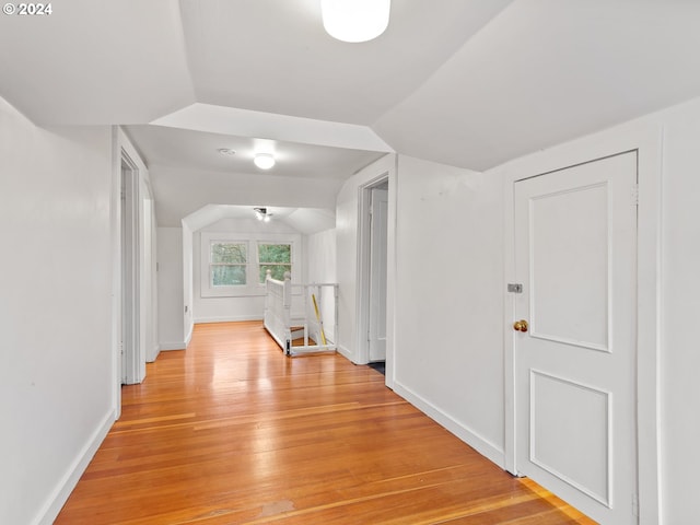 hallway with light wood-type flooring and vaulted ceiling