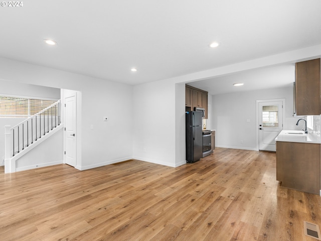 unfurnished living room with sink and light hardwood / wood-style flooring