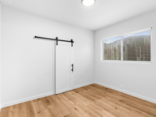 unfurnished room featuring light wood-type flooring and a barn door