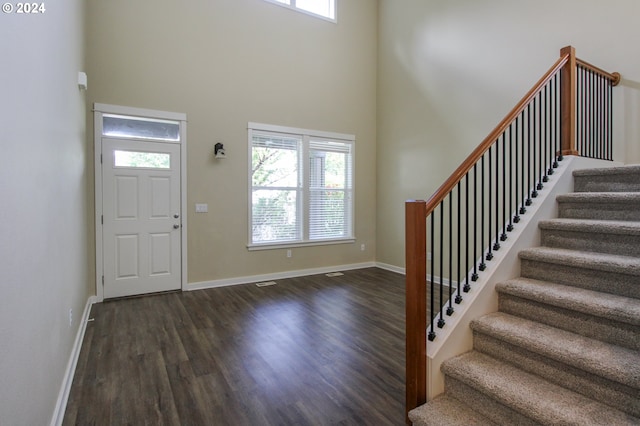 entryway with a towering ceiling, dark hardwood / wood-style flooring, and a wealth of natural light