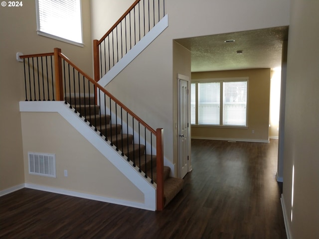 staircase with a textured ceiling and hardwood / wood-style flooring