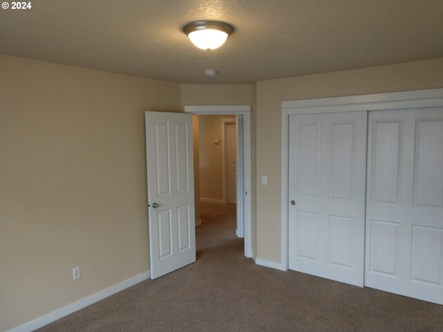 unfurnished bedroom featuring a closet, carpet floors, and a textured ceiling